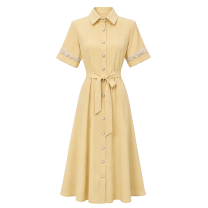 A pale yellow short-sleeve collared dress with a button front, matching fabric tie belt at the waist, and white floral lace trim on the sleeves, shown on a plain white background.
